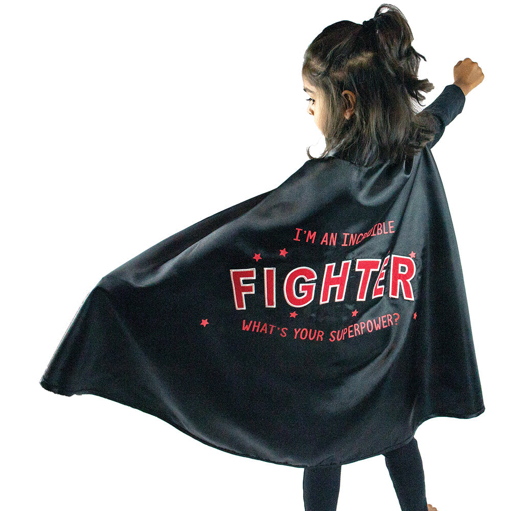 little girl in open the joy's red and black cape designed to empower children fighting illness or disease